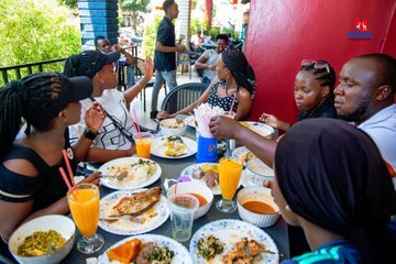 Group of teachers from Les Champion Education Center smiling and eating traditional local food on a MIANA Tour.