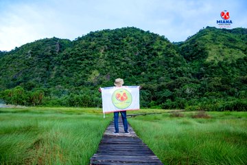 Group of MIANA tourists trekking through the Rwenzori Mountains in Uganda, with snow-capped peaks and lush green valleys in the background.